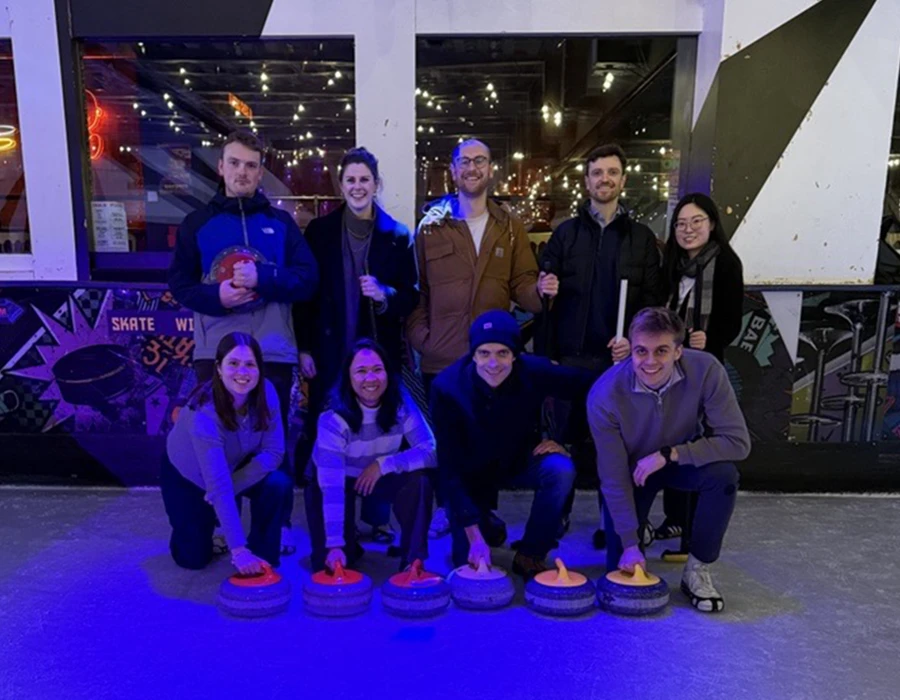 Colleagues posing for a photo while playing curling.