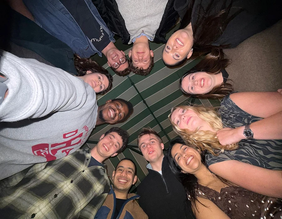 A group of colleagues stood in a circle as they look down at the camera.
