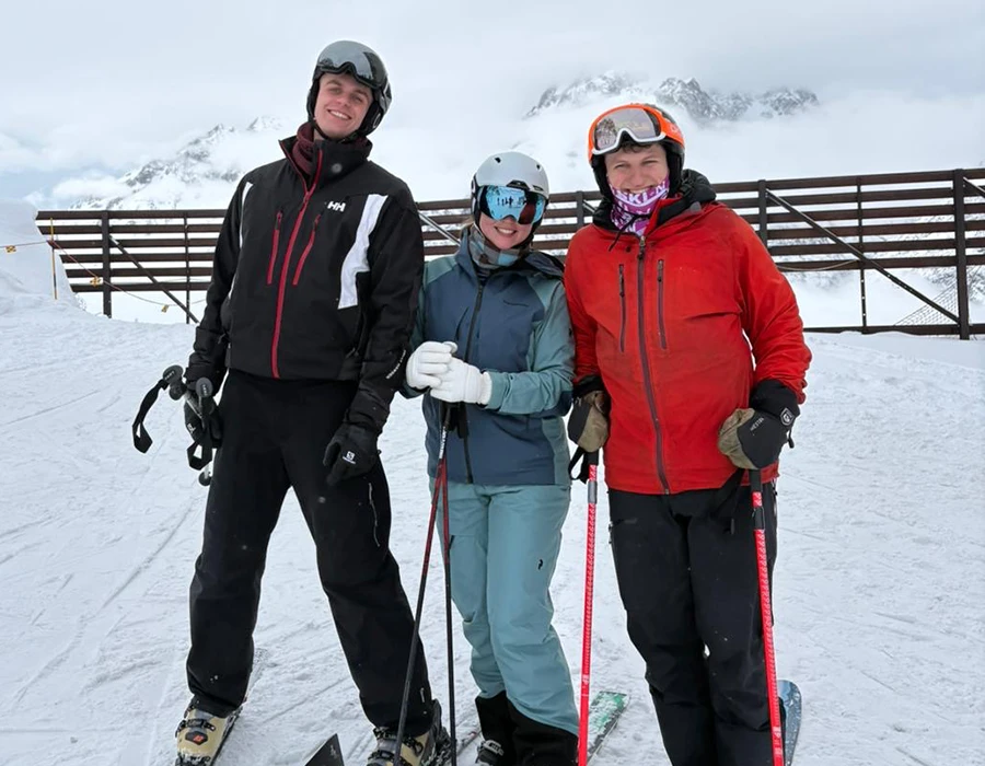 Three colleagues posing for a photo while skiing.