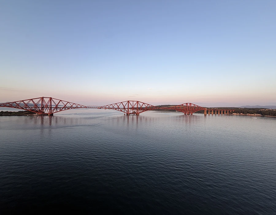 A landscape view of a red bridge at sunset.